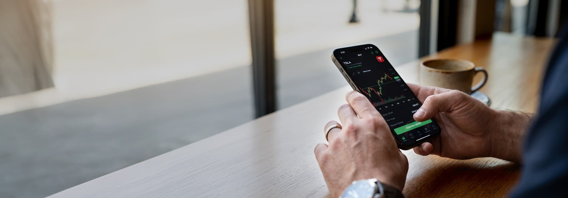 Hand holding a phone confirming a stock trade order